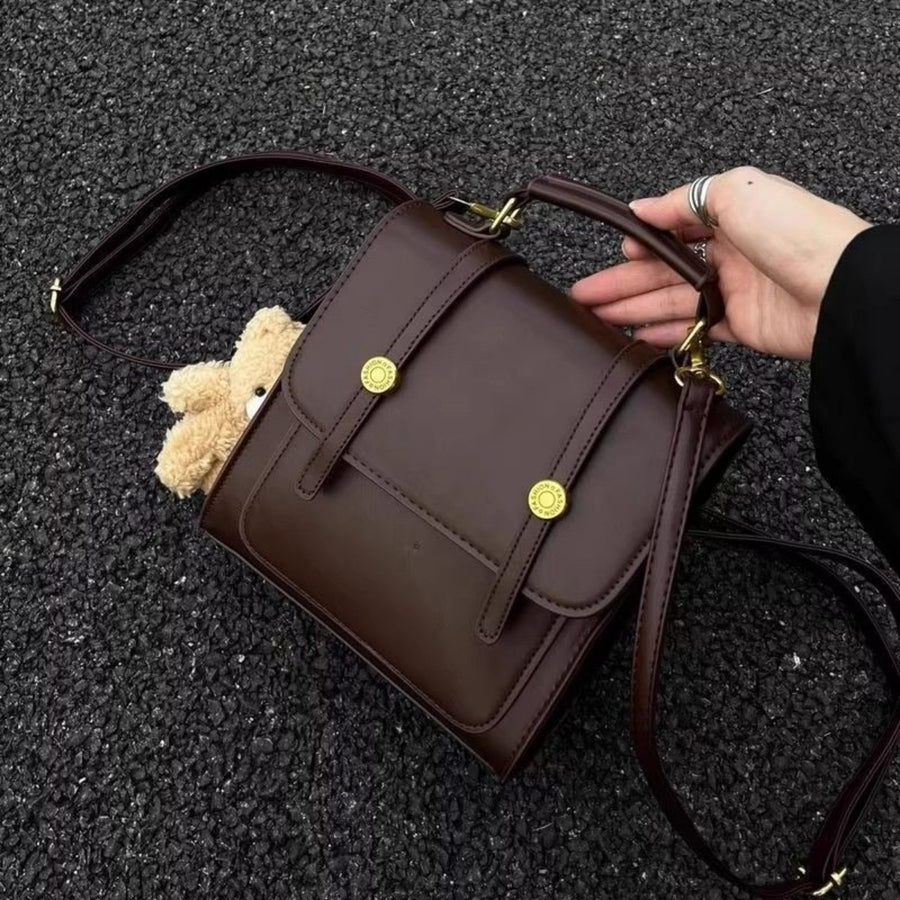 Mini brown pu leather backpack with decorative straps and gold hardware, teddy bear peeking out.
