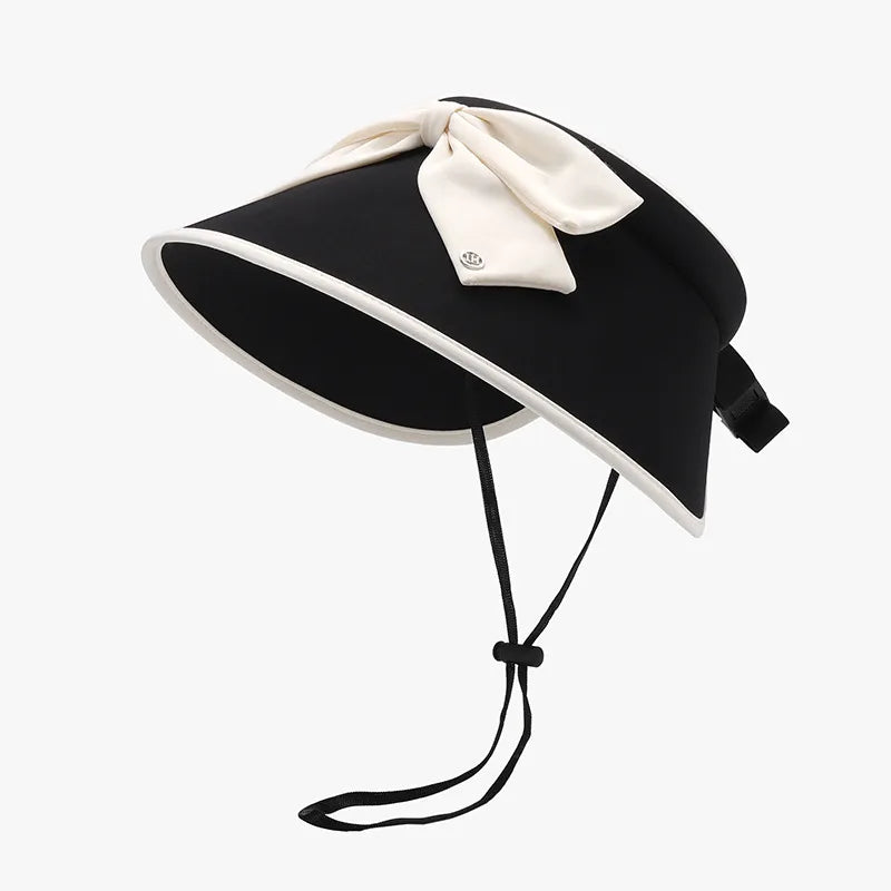 Black sun visor with ivory bow and contrast trim, adjustable chin strap.