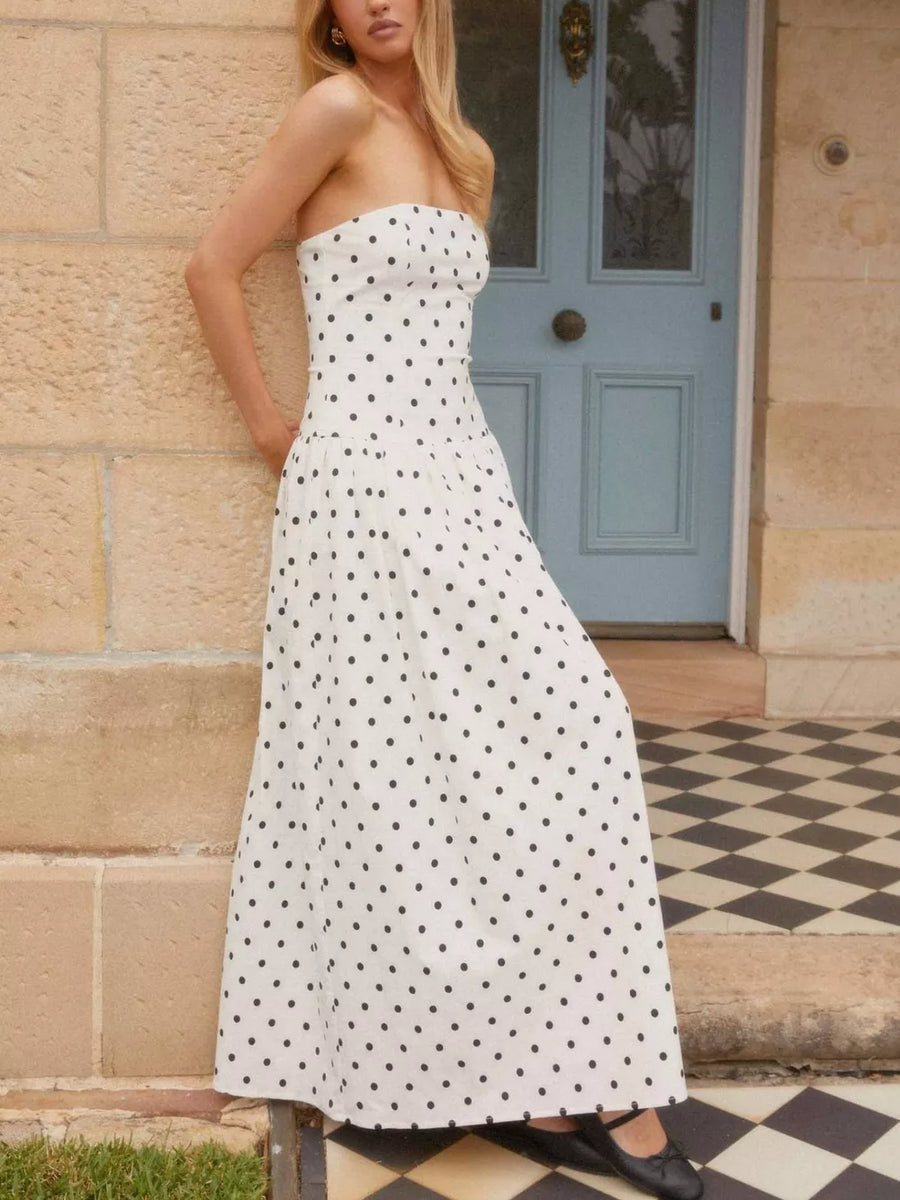 White polka dot strapless maxi dress with a fitted bodice and full skirt.