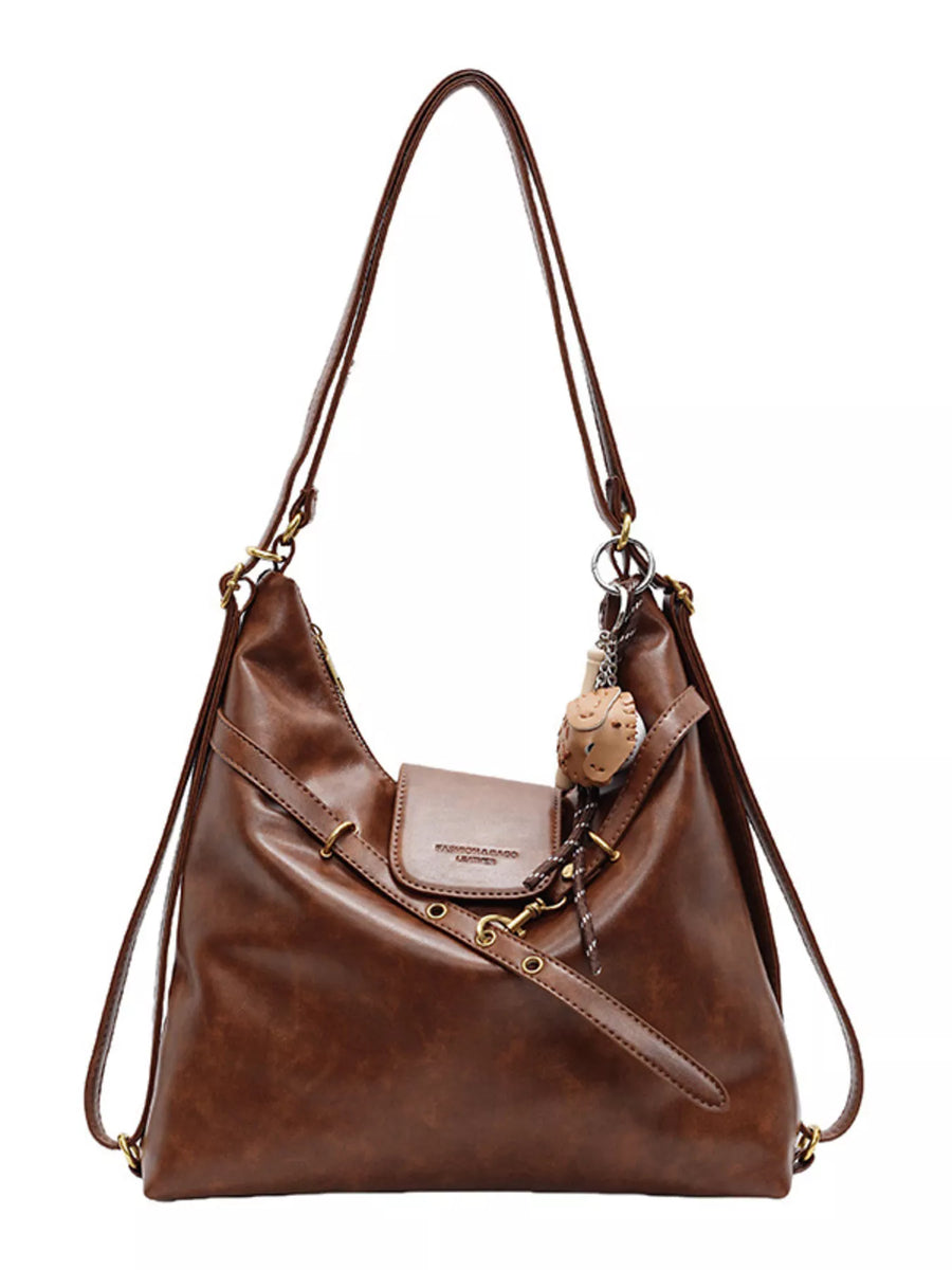 Brown convertible hobo bag made of PU leather with adjustable straps and a charm.