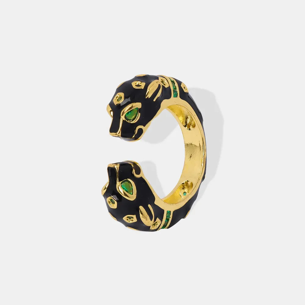 Gold panther head open ring with black enamel and green gemstone accents.