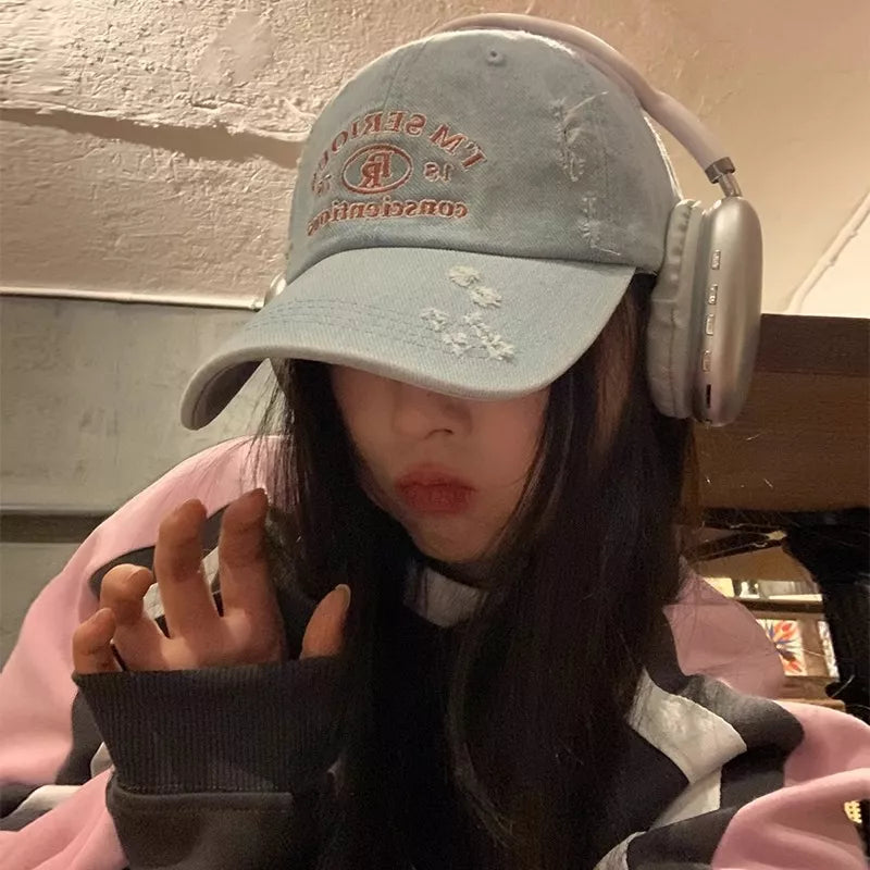 Light blue distressed denim baseball cap with embroidered text and silver headphones.