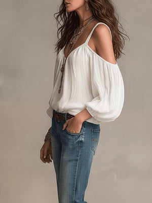 White cold shoulder balloon sleeve shirt with a V-neck, styled with jeans and necklaces.