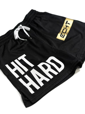 Black mesh training shorts with white HIT HARD graphic and gold logo detail.