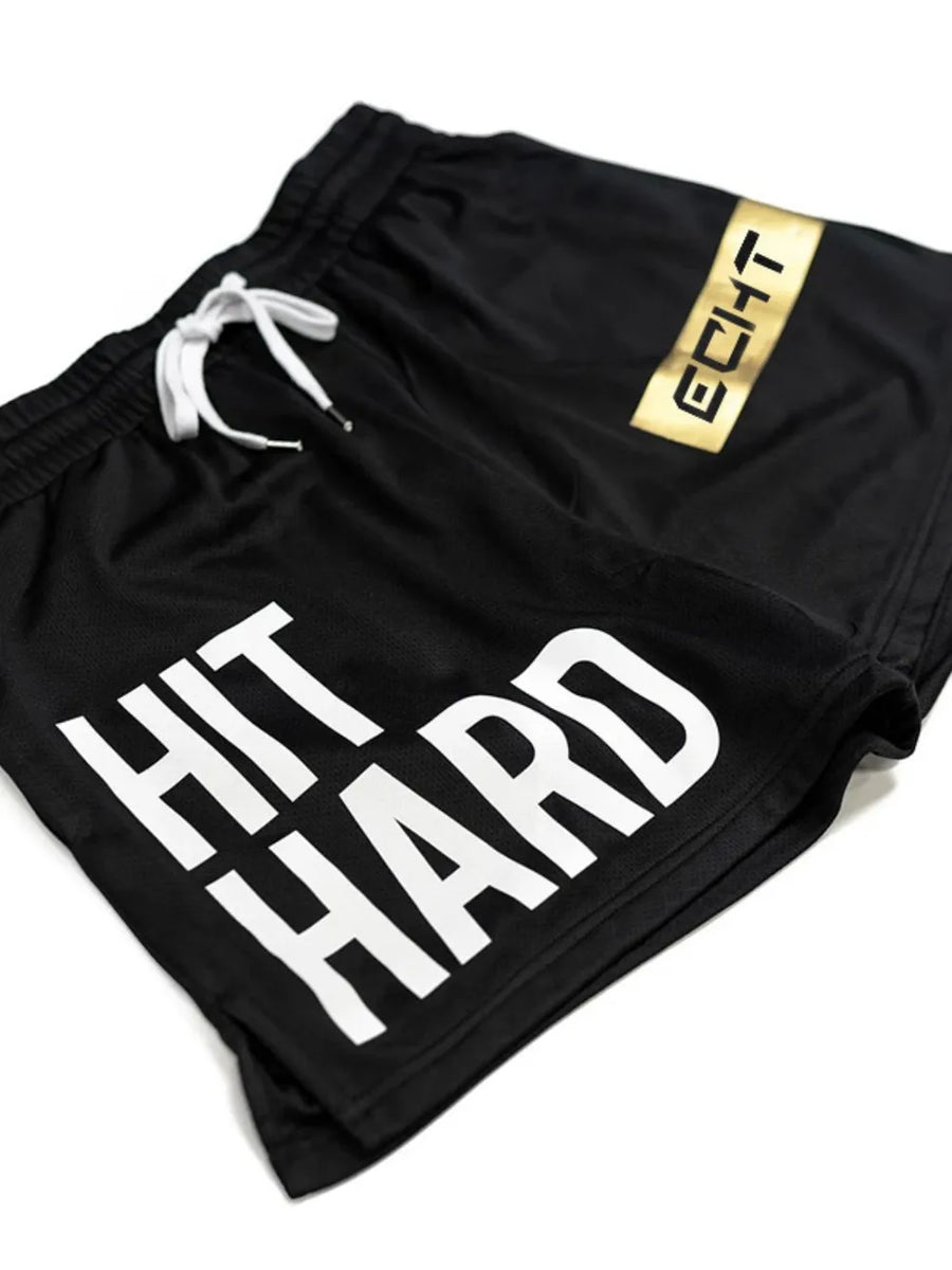 Black mesh training shorts with white HIT HARD graphic and gold logo detail.