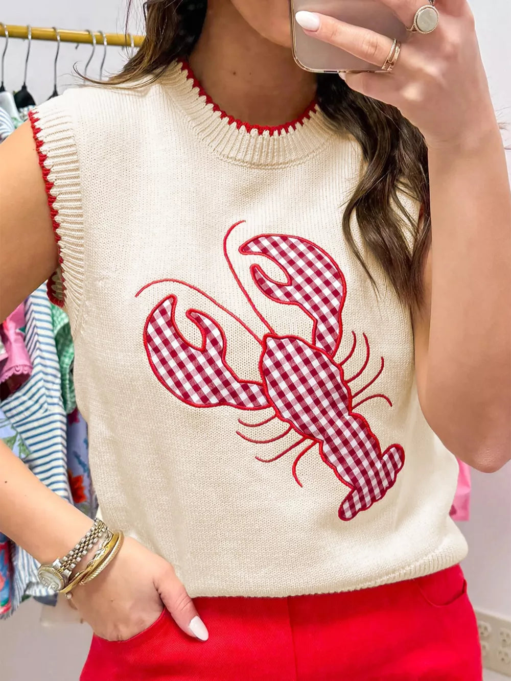 Beige knit sweater vest with red gingham lobster embroidery and red trim.