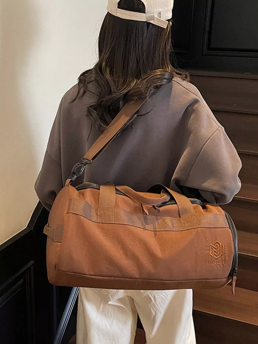 Brown Oxford cloth duffel bag with carry handles and adjustable strap, gym bag style.