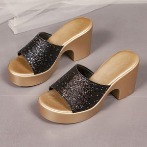 Black glitter open-toe slide sandals with chunky block heels and gold platform.