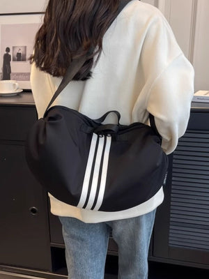 Black crossbody bag with white triple stripe detail and adjustable strap