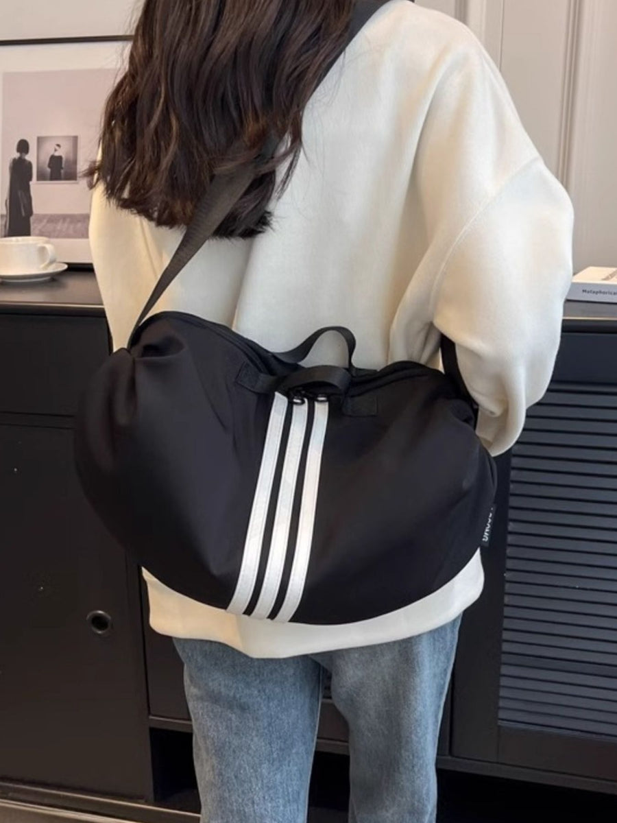 Black crossbody bag with white triple stripe detail and adjustable strap