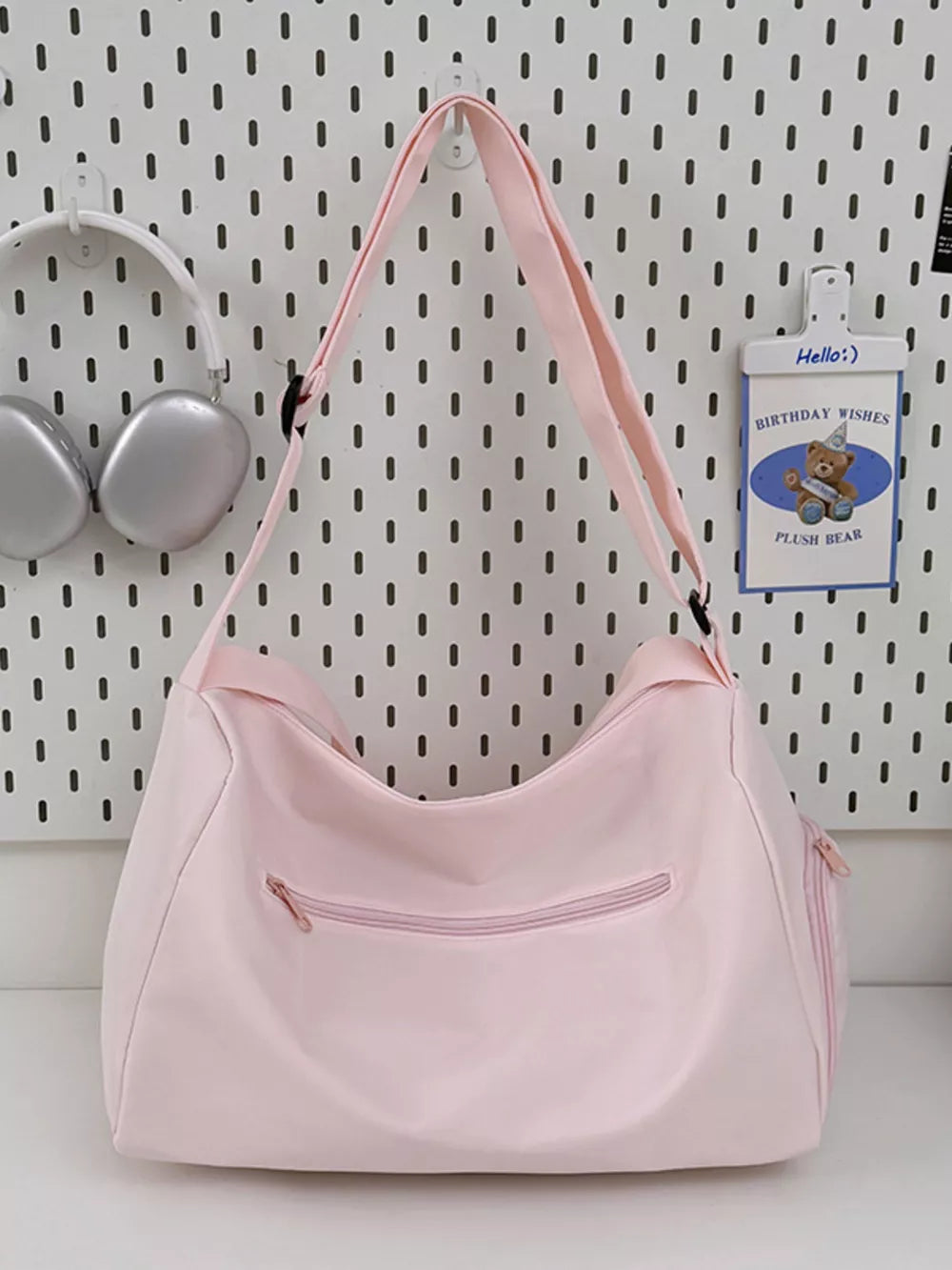 Blush pink travel pouch with adjustable strap and zippered pockets.
