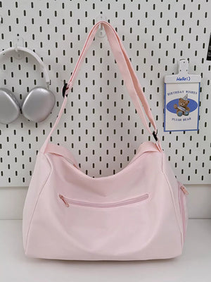 Blush pink travel pouch with adjustable strap and zippered pockets.