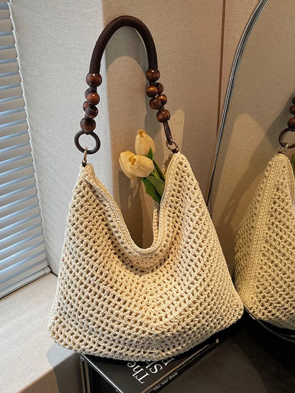 Ivory textured knit shoulder bag with a beaded handle and dark brown wooden beads.