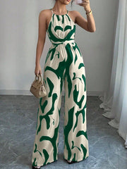 Elegant wide-leg jumpsuit in cream with abstract green print, halter neck, and draped bodice.