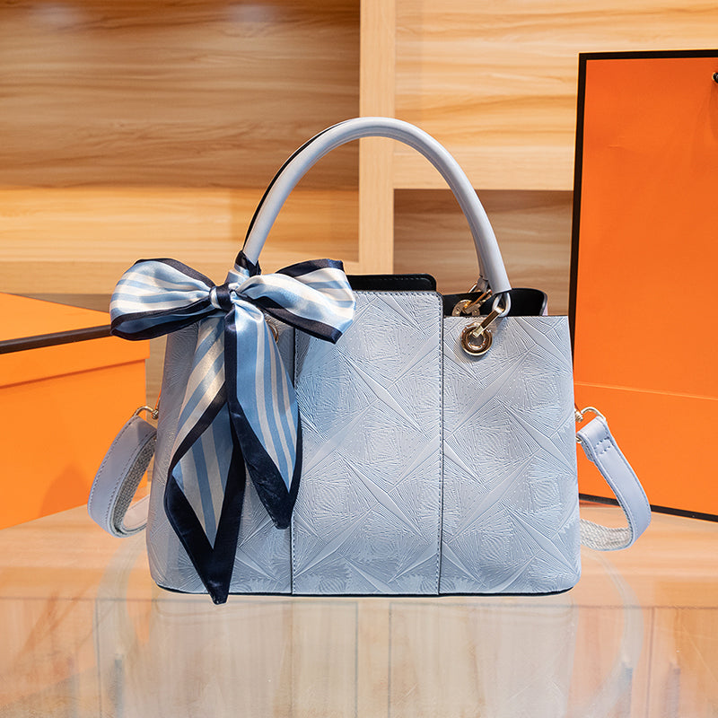 Light blue geometric embossed trapezoid tote handbag with decorative scarf.