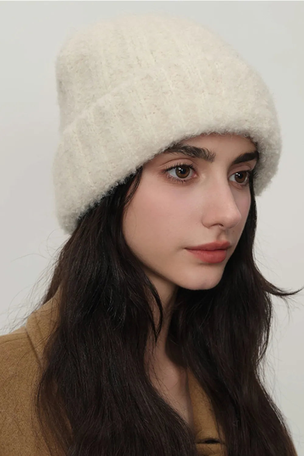 Textured bouclé knit beanie in cream, styled casually.