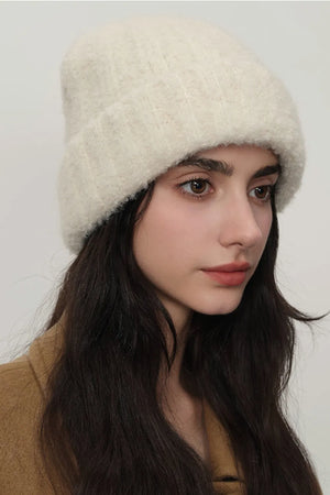 Textured bouclé knit beanie in cream, styled casually.