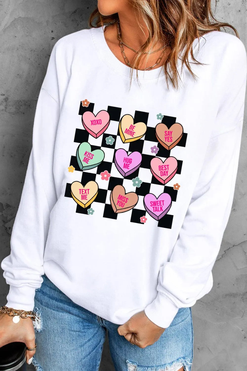 White sweatshirt with conversation heart graphic and checkered pattern.