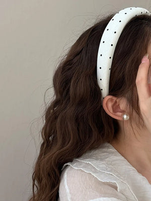 White padded headband with black polka dots and a handmade label detail.