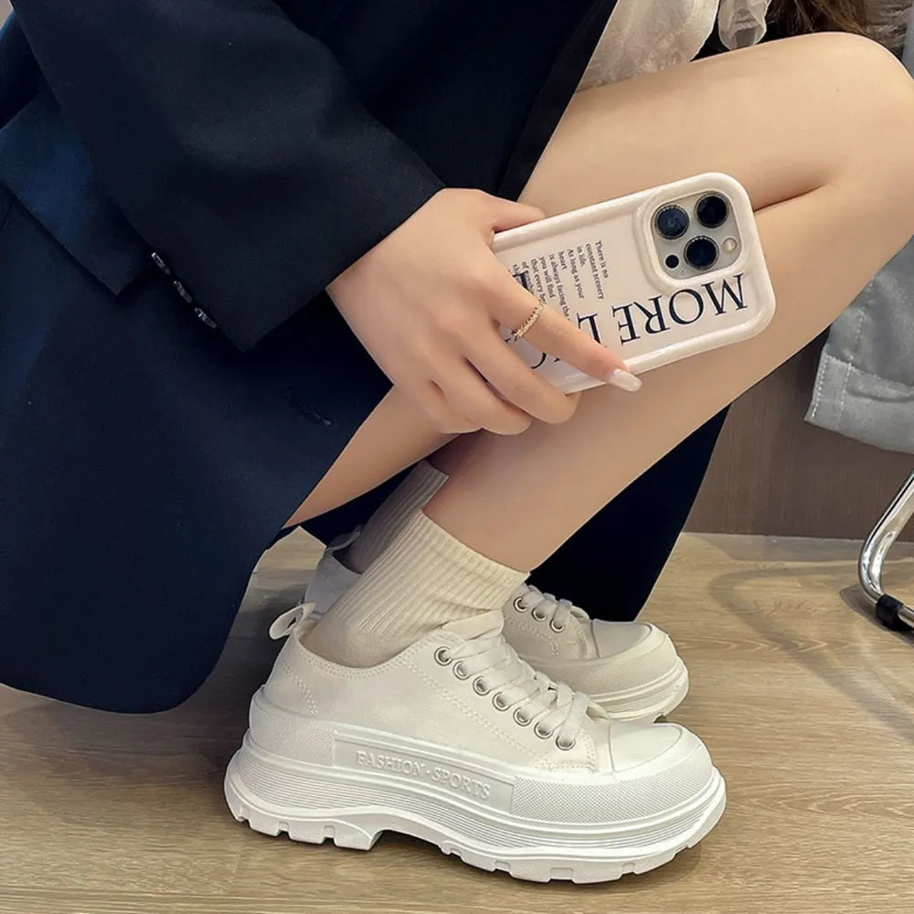 White canvas lace-up sneakers with chunky platform sole and embossed text detail.