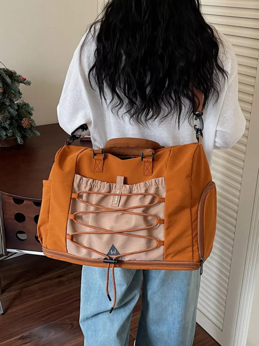 Large orange nylon duffel bag with bungee cord detail and tan accents