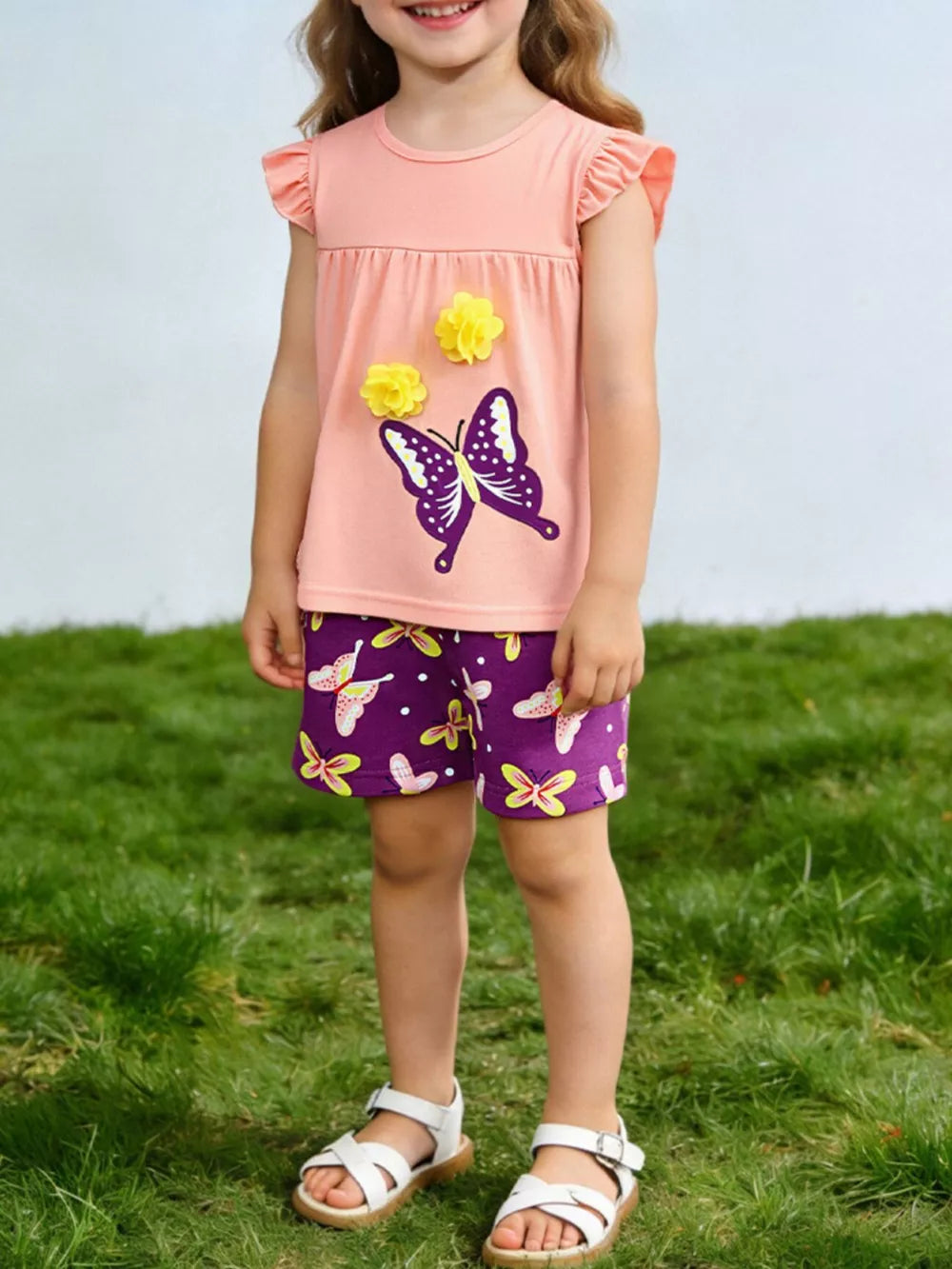 Peach ruffle sleeve top with butterfly applique and purple butterfly print shorts for toddlers.