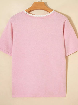 Pink knit top with short sleeves and delicate white lace trim at the neckline.
