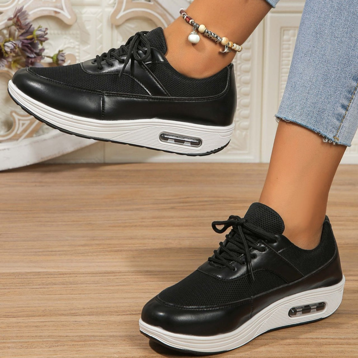Black lace-up wedge sneakers with breathable mesh and faux leather details.