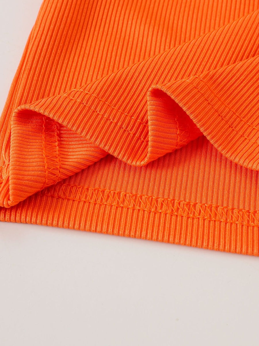 Orange ribbed cotton baby top detail with stitched hem and cuffs.