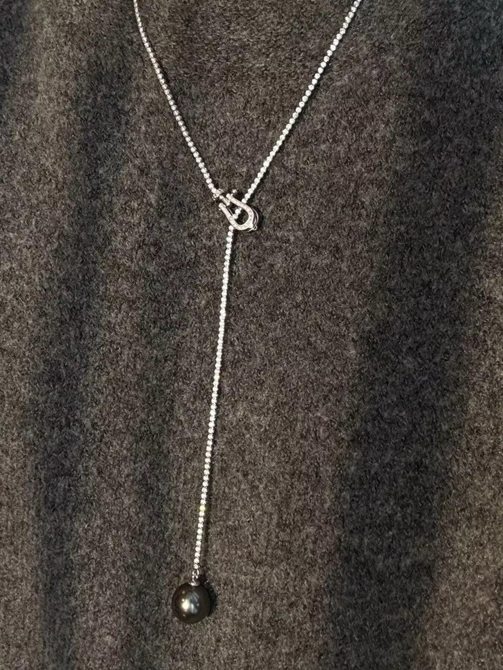 Lustrous pearl drop Y-necklace in dark gray with a delicate chain and horseshoe clasp.