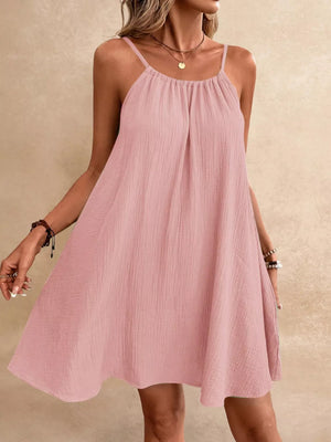 Pink spaghetti strap gauze dress with gathered neckline and A-line skirt.