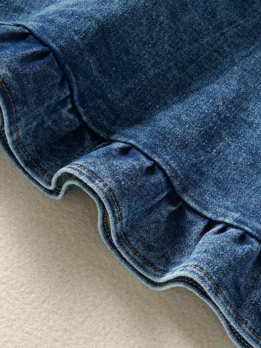 Denim overall dress detail with ruffles and contrast stitching.