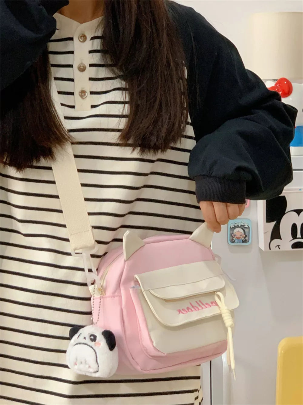 Pink crossbody bag with cat ears and a plush pug charm, featuring a front pocket.
