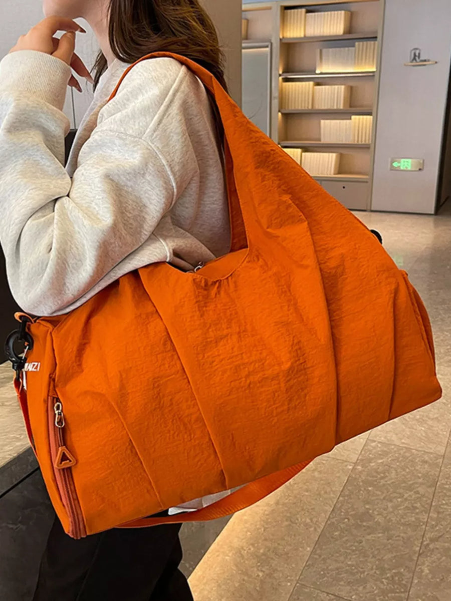 Orange nylon duffel bag with ruched detailing and side zip pocket.