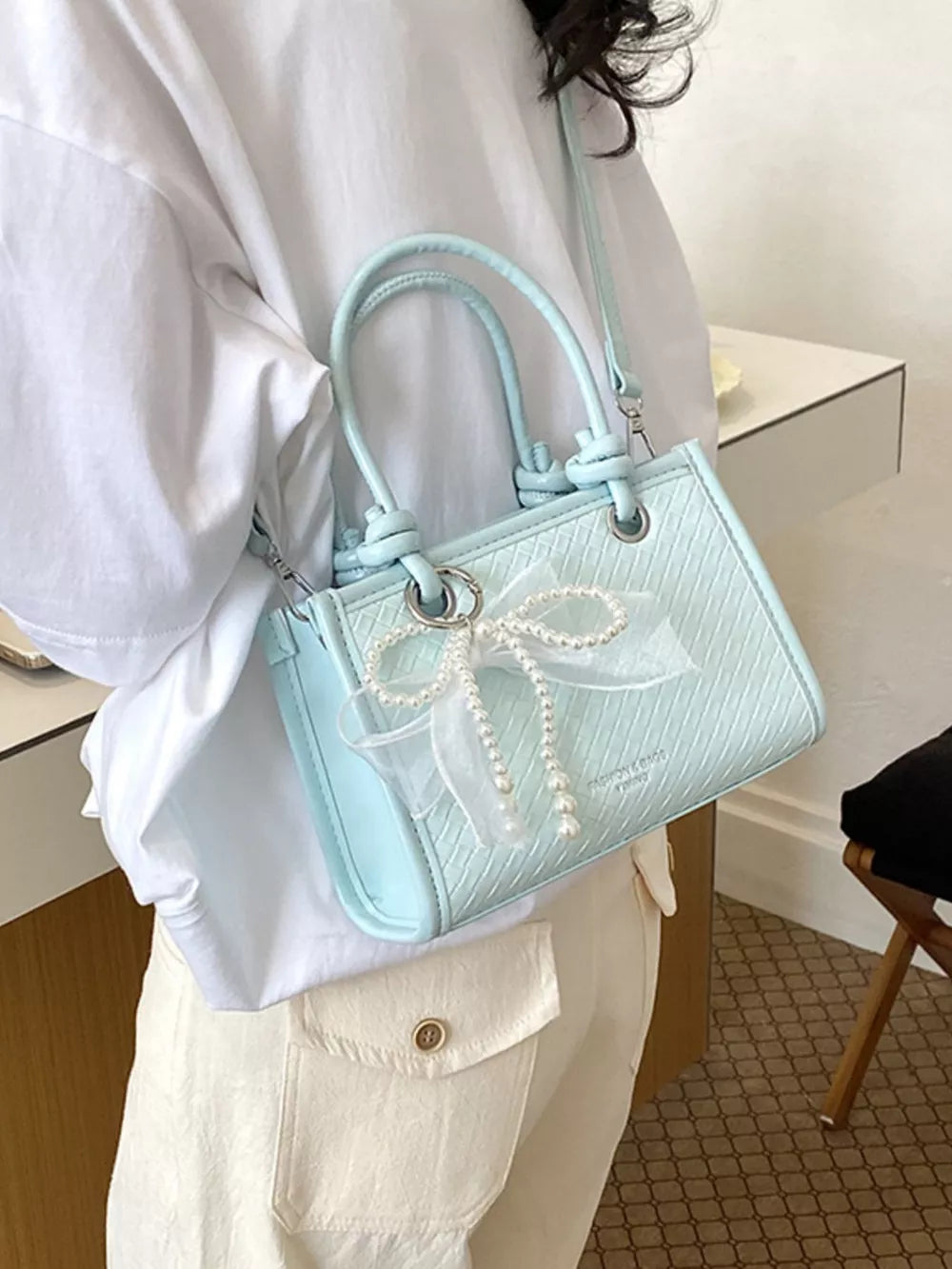 crossbody bag in sky blue featuring bow embellishment and boxy fit