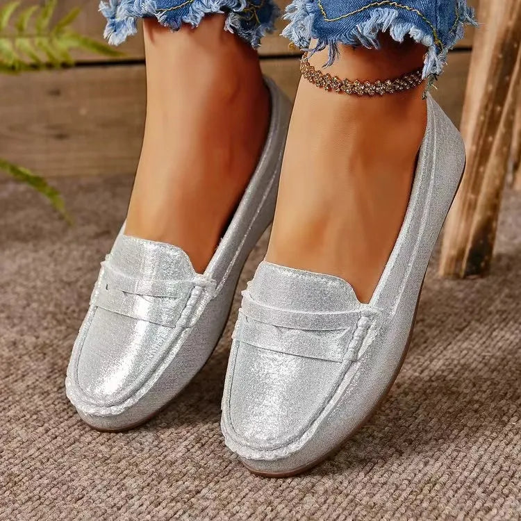 Silver metallic loafer flats with subtle stitching detail and a casual cut.