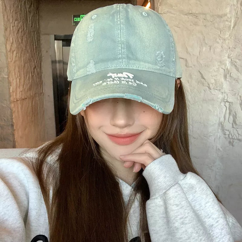 Distressed light green baseball cap with white embroidered text and frayed brim.