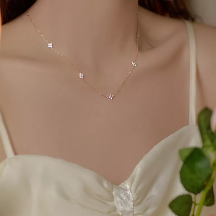 Rose gold necklace with delicate clover charms and sparkling accents.