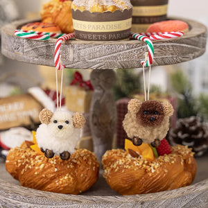 Woolly sheep ornament with pom-pom ears and brown face, hanging from a candy cane hook.