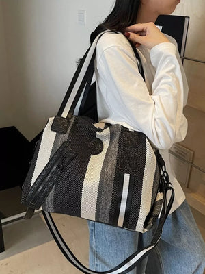 Chic striped medium duffle bag in black and white with a detachable strap.
