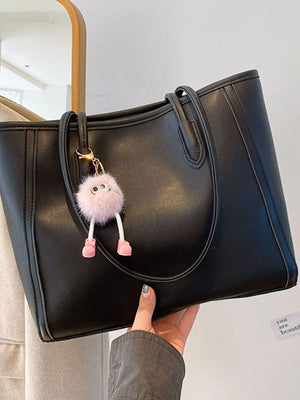 Black PU leather tote bag with a fluffy pink charm and gold hardware.