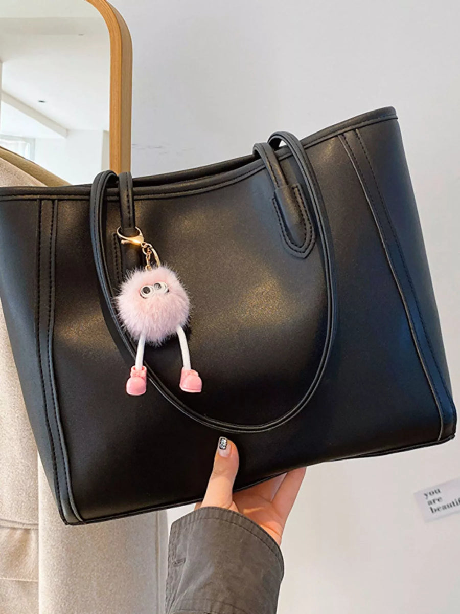 Black PU leather tote bag with a fluffy pink charm and gold hardware.