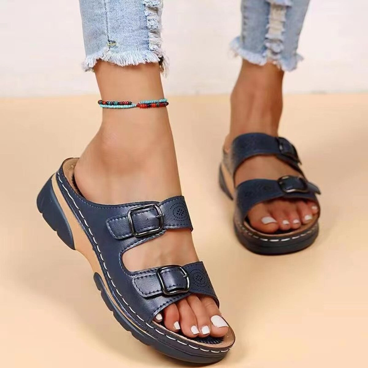 Dark blue double buckle open-toe sandals with perforated detail and contrast stitching.