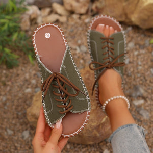 Green canvas lace-up open-toe flats with brown laces and white stitching detail.