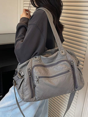 Gray faux leather shoulder bag with multiple zippered pockets and buckle details.