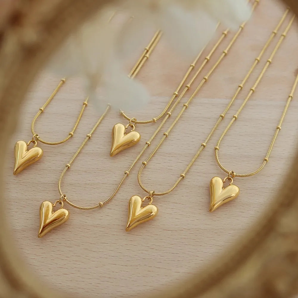 Gold heart pendant necklace with beaded chain, delicate and casual style.
