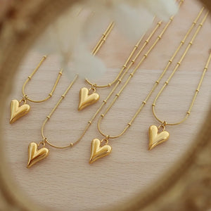 Gold heart pendant necklace with beaded chain, delicate and casual style.