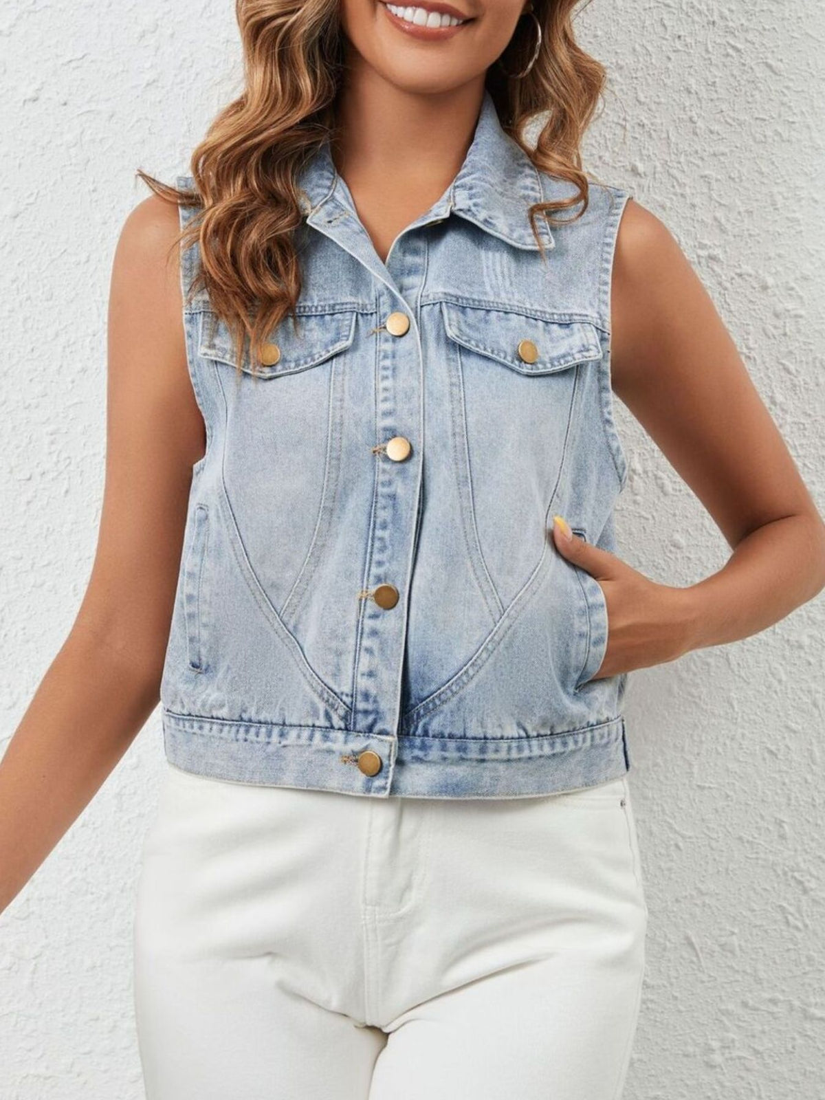 Cropped sleeveless light wash denim vest with button front and pockets.