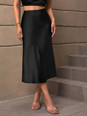 Black satin high-waisted midi skirt with a subtle sheen, styled with clear heels.