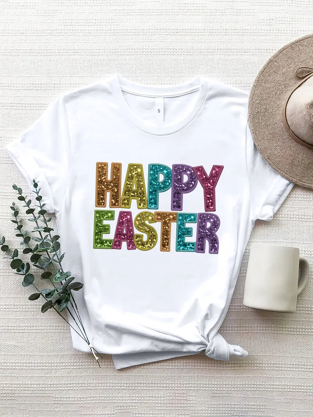 White t-shirt with glitter lettering that says Happy Easter in rainbow colors.